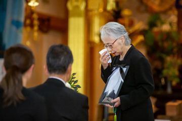 お葬式で挨拶する高齢者女性（喪主の挨拶・泣く）

