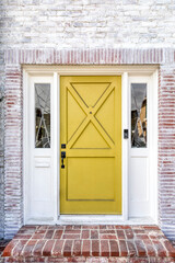 Yellow front door of a house with washed out looking red bricks.