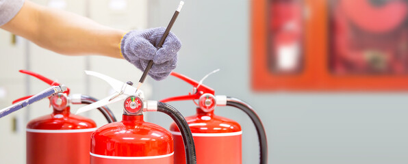 Fire extinguisher has hand engineer inspection checking pressure gauges to prepare fire equipment for protection and prevent emergency and safety rescue and alarm system training concept.