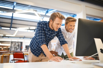 Working side by side. Cropped shot of two young male designers working on a desktop in their office.