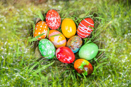 closeup, many beautiful painted easter eggs as grass blurred background. concept for good friday, easter monday, spring full moon. copy space on top for text or design. garden, nobody, selective focus