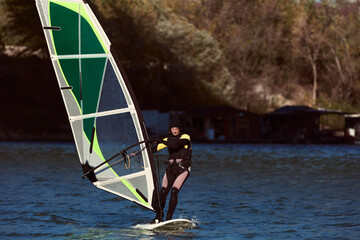 Naklejka premium Windsurfer surfing on a windy day at the city river.