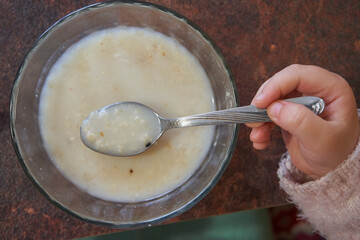 spoon with porridge,child holding a spoonful of porridge top view
