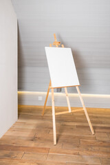Painting stand wooden easel with blank canvas poster sign board isolated. wooden tripod with blank white paper.
