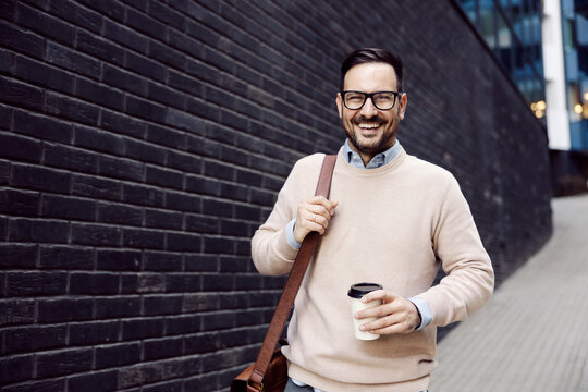 An Urban Man Holding Coffee To Go On The Street And Smiling At The Camera.