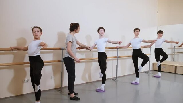 Group of boys on ballet gymnastics class with their teacher performing exercise. Instructor choreographer controls students. Dancing sports education in ballet choreography school for children.