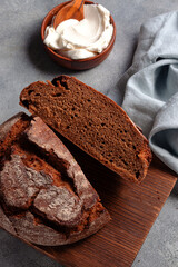 artisan dark sliced unleavened bread with cottage cheese searved on cutting board. gray stone background