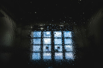 A foamy and bubbly car windscreen overlooking the exit of a carwash with square windows