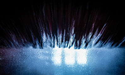 Abstract and dramatic bubbles and bristles with a blue tint on the windscreen of a car going through a carwash. 