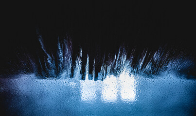 Abstract and dramatic bubbles and bristles with a blue tint on the windscreen of a car going...