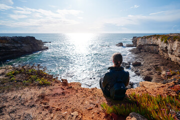 Tourism concept. Young traveling woman with rucksack enjoying ocean view.