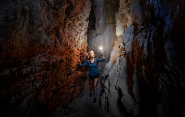 Young woman exploring a cave digged in the mountain. - obrazy, fototapety, plakaty