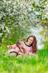 Fototapeta premium mother and daughter in identical dresses lie in the grass