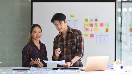 Obraz premium Two professionals web developers standing in bright modern office and smiling to camera.