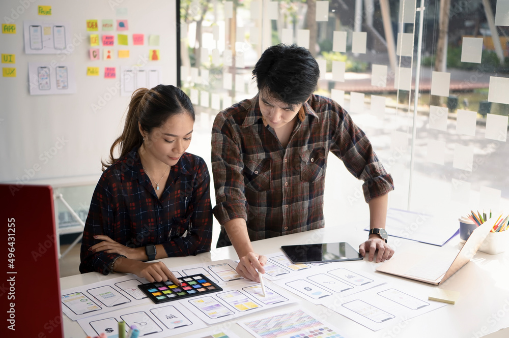 Poster two young designers brainstorming about mobile application interface wireframe design together.
