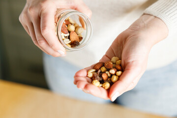 Nuts spilling from jar in woman's hand