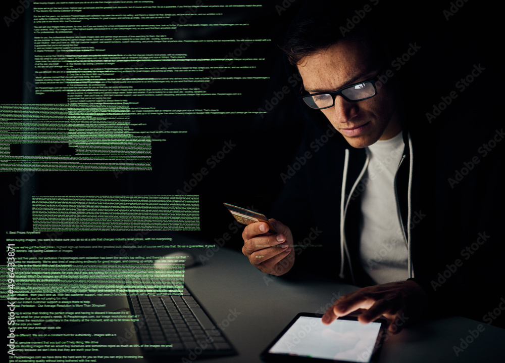 Fototapete One more touch and all your information will be mine. Cropped shot of a young hacker using a tablet to commit credit card fraud in the dark.