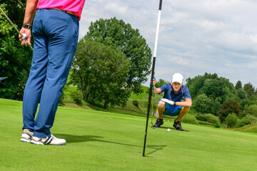 Junger Golfer beim Lesen des Ballwegs auf dem Grün 