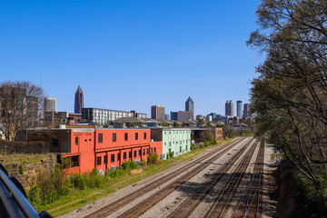 five sets of railroad tracks surrounded by gravel with colorful buildings along the trees and...