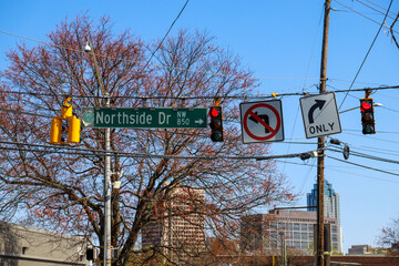 two traffic signals with red lights and a white and green sign that reads "Northside Drive" with a no left turn sign and a right turn only sign in downtown Atlanta Georgia USA