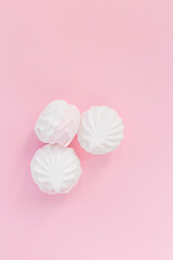White airy and soft marshmallows on a pink background view from above. Sweet delicate flatlay dessert