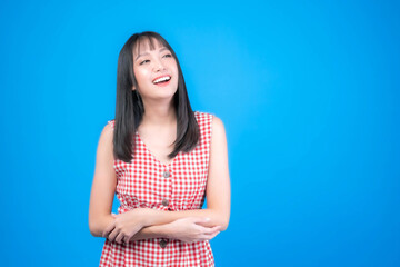 Portrait of Beautiful Asian woman cute girl in red dress with bangs hair style , laugh and smiling good mood isolated blue background -