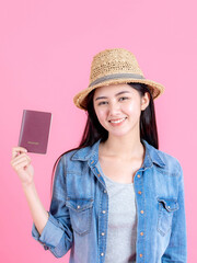 female traveler wearing traw hat is holding passport Portrait of pretty smiling happy teenager on pink background