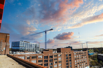 tall red brick buildings and glass skyscrapers with tall tower cranes in the cityscape with blue sky and powerful clouds at sunset at Ponce City Market in Atlanta Georgia USA - obrazy, fototapety, plakaty