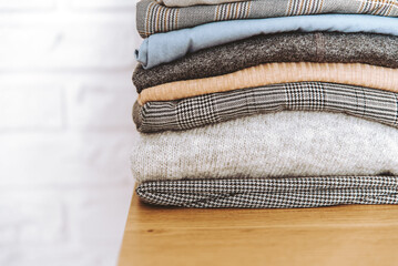 Stack of folded casual clothes on table with copy space. Pile of cotton clothes and sweaters.