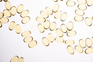 Pattern of transparent golden omega 3 capsules on a white background
