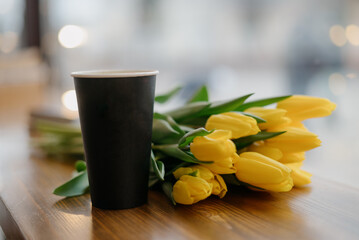 paper cup of coffee with a bouquet of flowers on the table