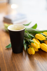 paper cup of coffee with a bouquet of flowers on the table