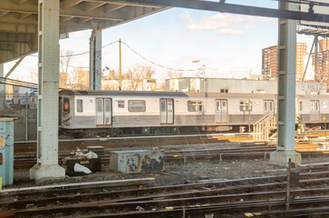 Trains at Coney island, Brooklyn Subway Station, New York City, view through Subway Window during sunny winter day with cloudy sky, residential Buildings in the background, horizontal