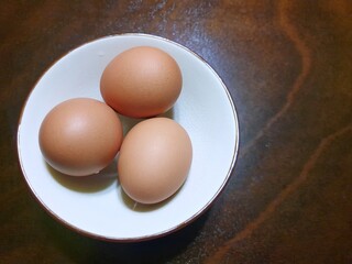 Top view of egg on white plate isolated on wooden table as a background, Copy space, ready to cook, Selective focus