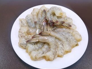 Top view raw prawns on white plate isolated on brown background, Raw big tiger shrimp, copy space,  for grill or cooking, Selective focus