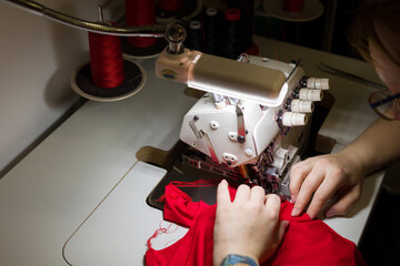 Woman is sewing fabric on an overlock machine