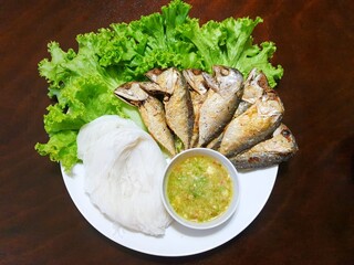 Thai food style, Top view of Fried Mackerel and Spicy seafood dipping sauce, Rice noodles on the lettuce on the wooden table as a background Ready to serve or eating, Miang Pla Too is Thai traditional