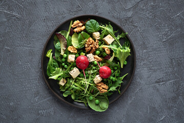Green salad with tofu and chia seeds. Mixed salad with tofu hazelnuts and tofu on rustic table. Fresh diet salad served in plate.