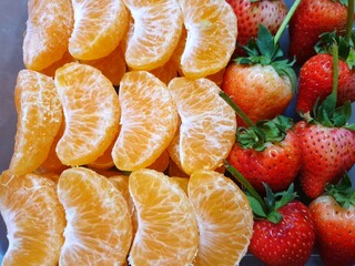 Top view of orange and strawberry fruit as a background for sale on market stand in Thailand, Fresh fruit ready to eat or making drinks and salads, Healthy concept