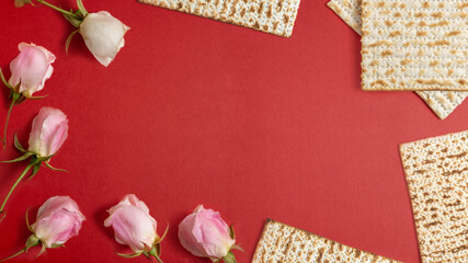 Rose flowers and matzah for Jewish holiday Pesach on red background with copy space.