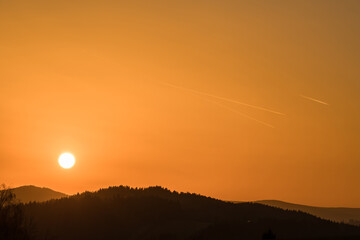 Nahaufnahme der Sonne während Sonnenuntergang über dem Horizont mit Berg Hügel Landschaft im...