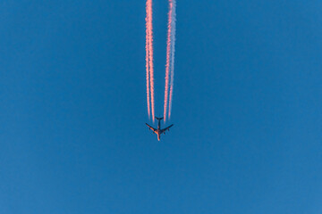 Flugzeug an einem blauen wolkenlosen Himmel mit farbigen bunten Kondensstreifen ohne Wolken...