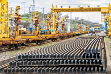 Lengths of rail stacked along track mounted cranes at depo
