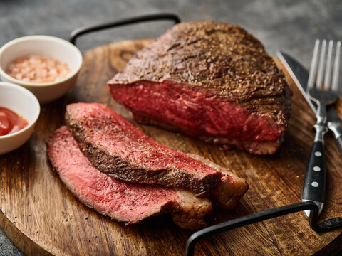 Grilled ramp cap steak on a cutting board. Barbecue Grilled rump cap or brazilian picanha beef meat steak in a wooden tray