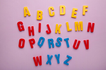 Magnetic plastic alphabet letters on purple background.