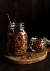 Big and small jars with homemade granola on the wooden serving desk