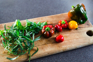 freshly picked capiscum bell peppers and mixed herbson top of wooden cutting board, simple...