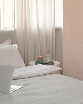 close-up of the corner of the bed with laptop and table with candles and Buddha