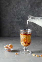 Iced coffee in a tall glass with cream, ice cubes, latte. Cold summer drink