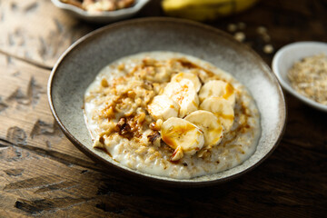 Healthy oatmeal porridge with banana and walnut - obrazy, fototapety, plakaty